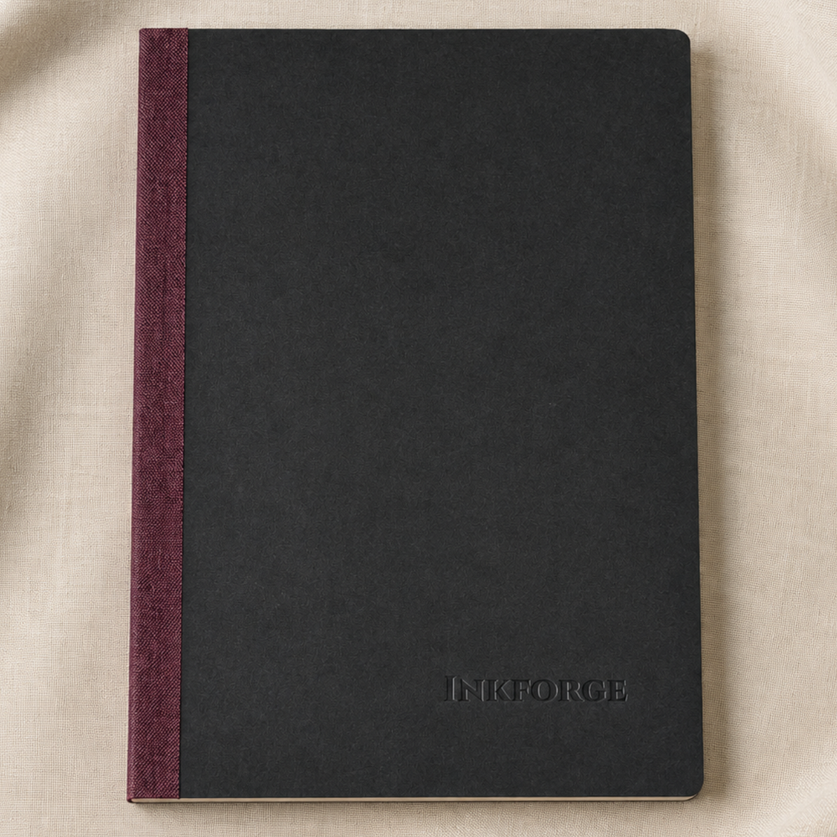 A black hardcover notebook with a linen burgundy spine, placed on a beige fabric background. The brand name 'INFORGE' is embossed on the bottom right corner of the cover.