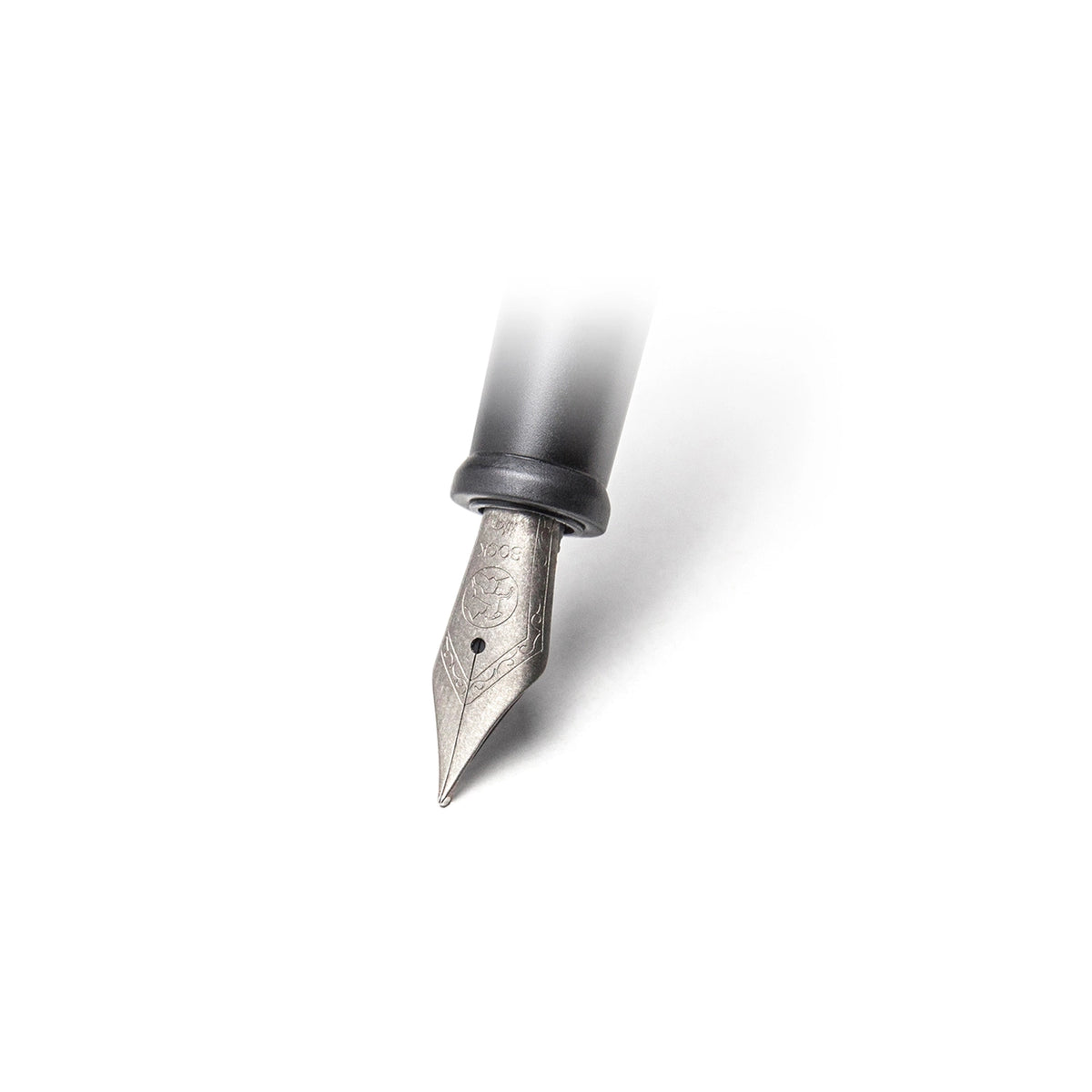 A close-up of a fountain pen nib and grip, showing a matte titanium nib with engraved detailing and a black grip, isolated on a white background with a soft shadow.